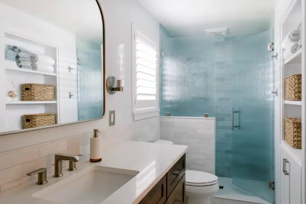 Bathroom with wood vanity and rain pattern shower glass installed by bathroom remodeling contractors in Tallahassee, FL