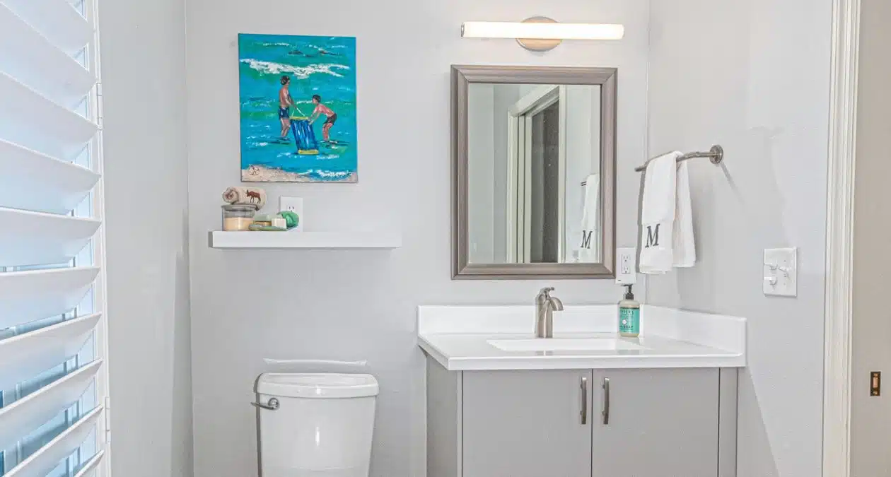 herringbone tile shower with brass fixtures beside white quartz vanity with gold faucet in Craft Bathroom