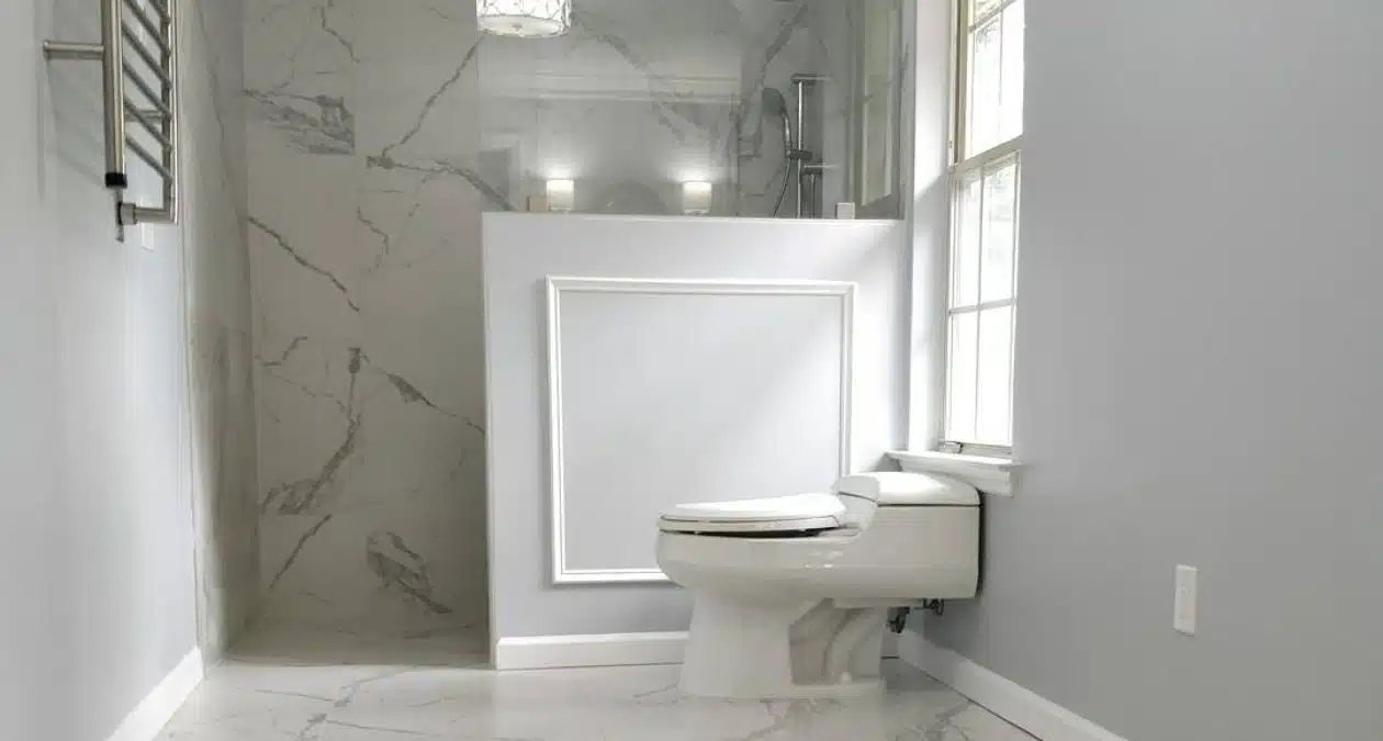 herringbone tile shower with brass fixtures beside white quartz vanity with gold faucet in Craft Bathroom